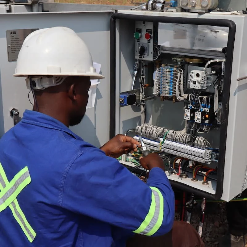 Electrical technician working at an open industrial control cabinet